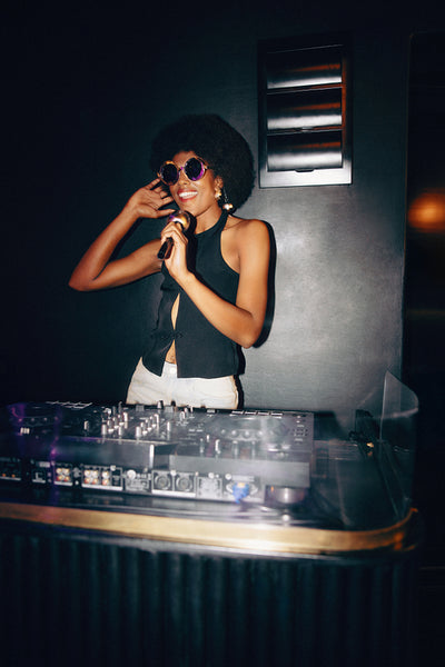 Stylish African female DJ holding a microphone at a lively nightclub event