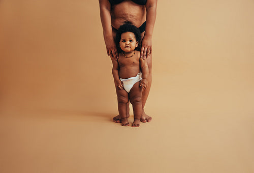 Baby standing with mother.