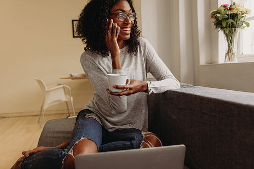 Woman managing business from home with mobile phone and laptop
