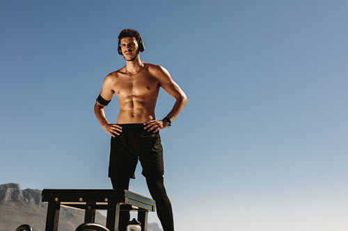 Man doing fitness training at the beach listening to music