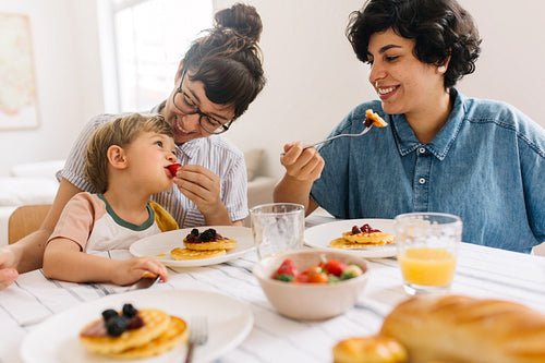 Lesbian couple eating breakfast with their son at home