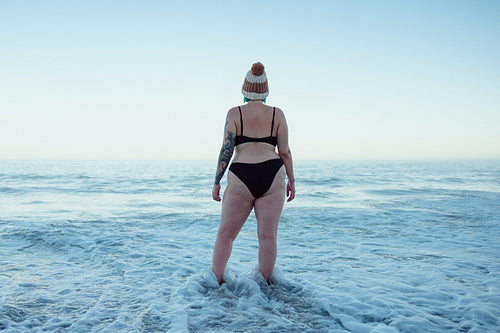 Female winter bather watching the sea waves at the beach