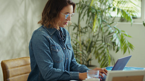 Female business professional woman working on laptop and taking notes in office