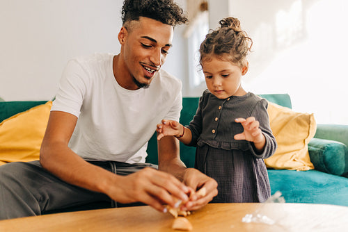 Happy father and daughter opening a fortune cookie at home