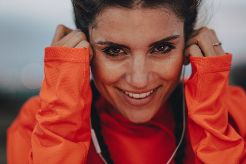 Smiling female runner adjusting her earphones