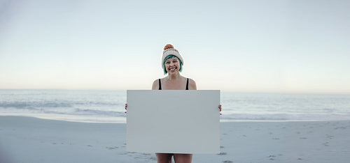 Cheerful winter bather holding a banner at the beach