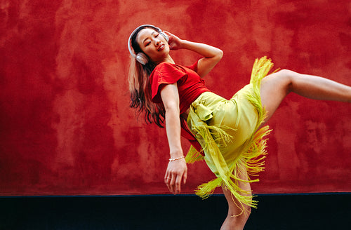 Listening woman dances with headphones in an urban street