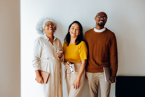 Three colleagues smile together in a casual office
