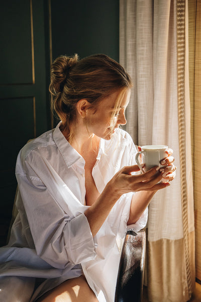 Happy young woman enjoying a cup of coffee in a hotel