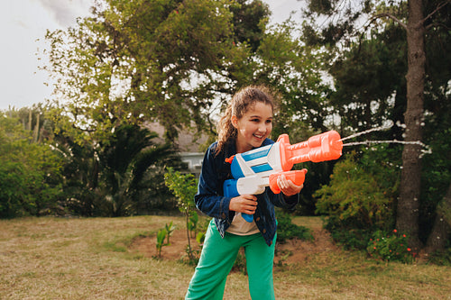Young girl enjoying outdoor play with a vibrant water blaster