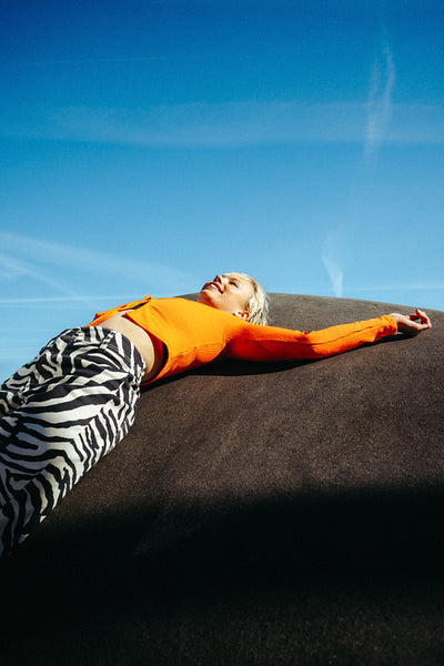 Woman relaxing outdoors on a large rock under a blue sky