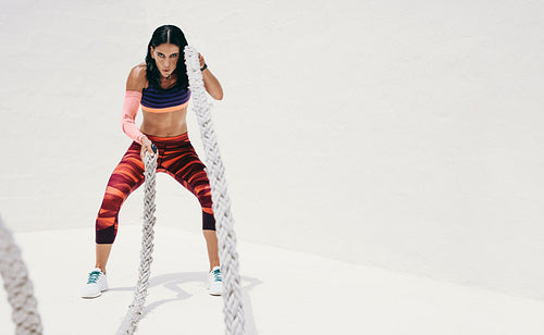Woman doing fitness workout using battle ropes