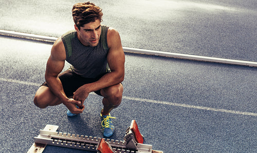 Sprinter sitting beside a starting block on running track