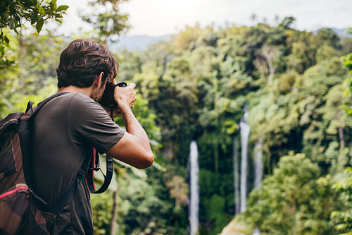  Male hiker photographing a waterfall in forest
