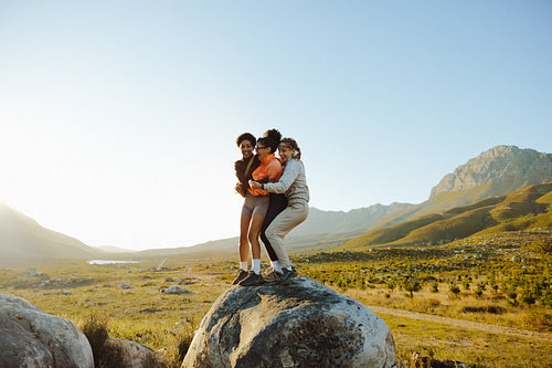 Friends hugging on a scenic hilltop