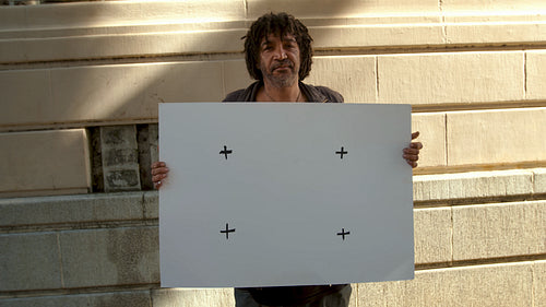 Homeless person holding a blank billboard outdoors