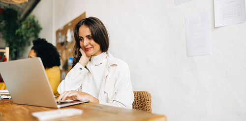 Professional business woman working on a laptop in her fashion design office