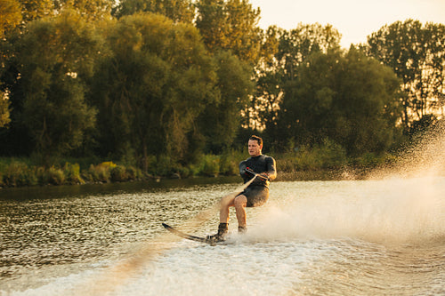 Man water skiing on lake behind a boat