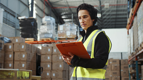 Woman in a reflective jacket taking stock in a fulfilment warehouse