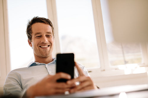 Freelancer looking at mobile phone sitting at home