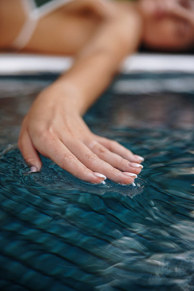 Female hand touching the water surface in a pool