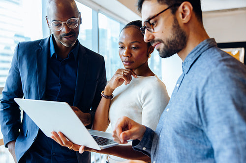 Group analyzing laptop work in an office setting
