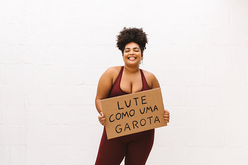Cheerful woman with "Fight like a girl" signboard