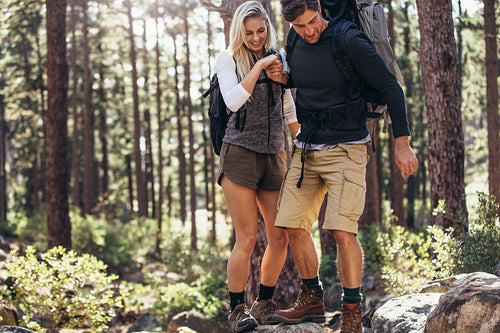 Hiking couple walking on rocks in forest wearing backpacks