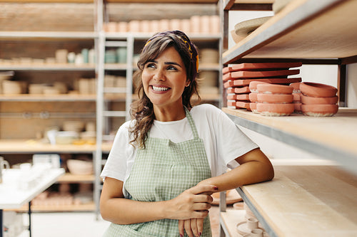 Happy female ceramist contemplating new ideas for her pottery