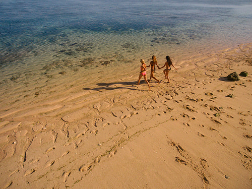 Three young woman running into the sea