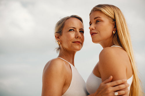 Elegant women showcasing luxury jewelry against a soft cloudy sky backdrop