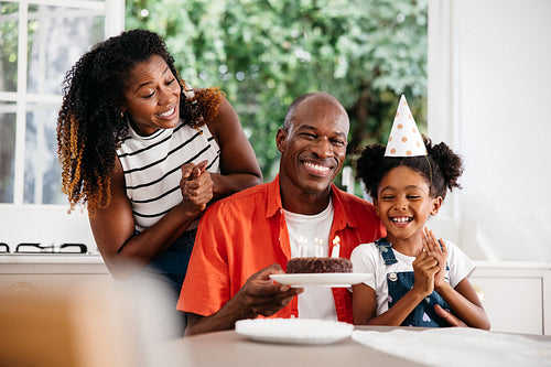 Family celebrating young girl's birthday with cake