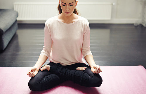 Relaxed young lady meditating at home