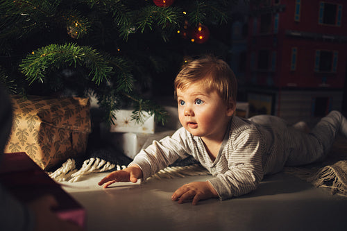 Cute baby boy lying by christmas tree