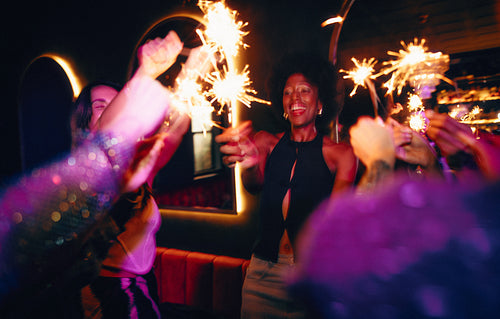 People enjoying a festive celebration with sparklers in a vibrant setting