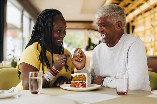 Senior couple eating a cake together in a cafe