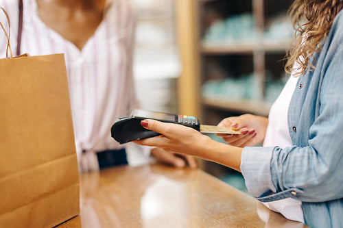 Ceramic store owner swiping a credit card while serving a customer