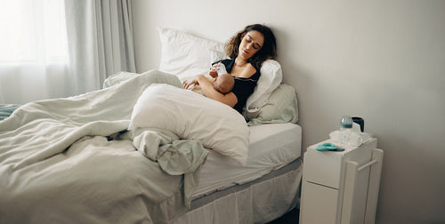 Woman in bed bottle feeding baby