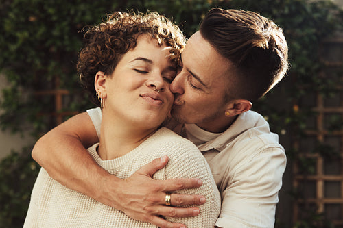 Flirty young man kissing his girlfriend outdoors