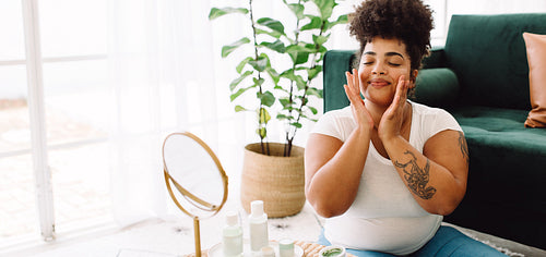 Woman applying facial cream at home