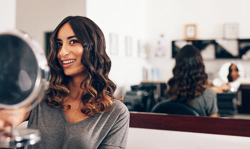 Woman holding a small round mirror at beauty salon