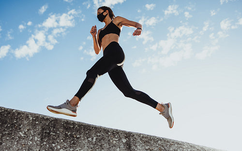 Sporty woman doing running workout with face mask