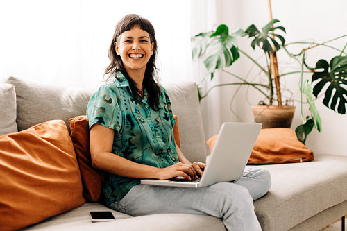 Happy young woman updating her personal blog at home