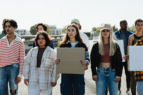 Diverse group of young adults holding placards during a daytime outdoor protest