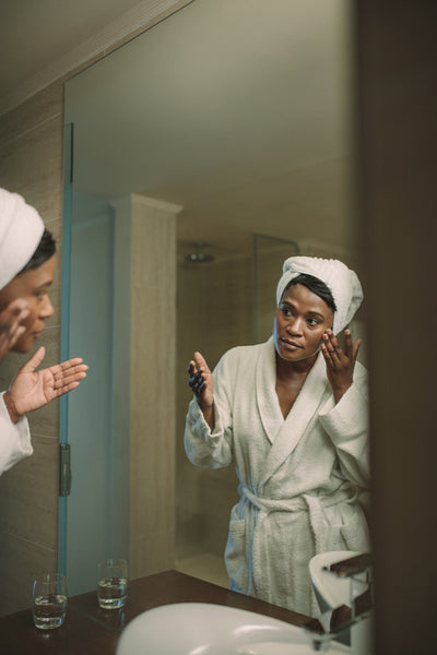 Reflection of mature woman in the mirror applying facial cream