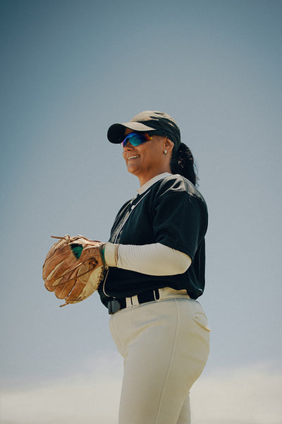 Happy baseball pitcher standing on the field with a glove ready for action