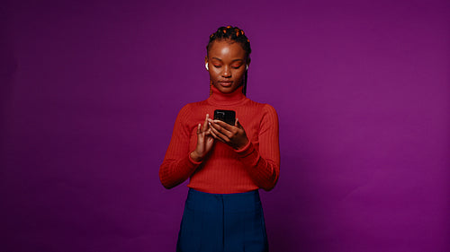 Young woman selecting and singing along to music on her phone while dancing