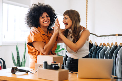 Cheerful thrift store owners high fiving each other in their shop
