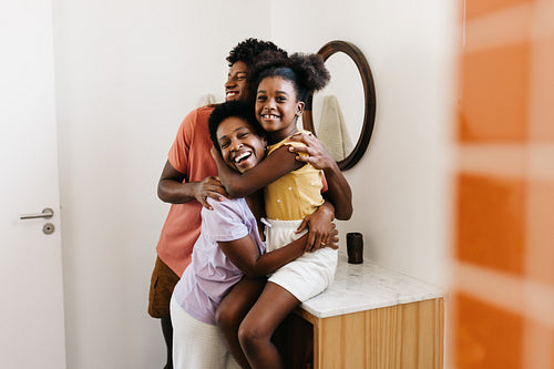 Mom hugging her son and daughter at the bathroom sink, smiling happily