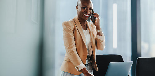 Portrait of a woman smiling and speaking on a smartphone in office